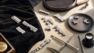 Platinum watch bracelet links and watchmaking tools on a workbench