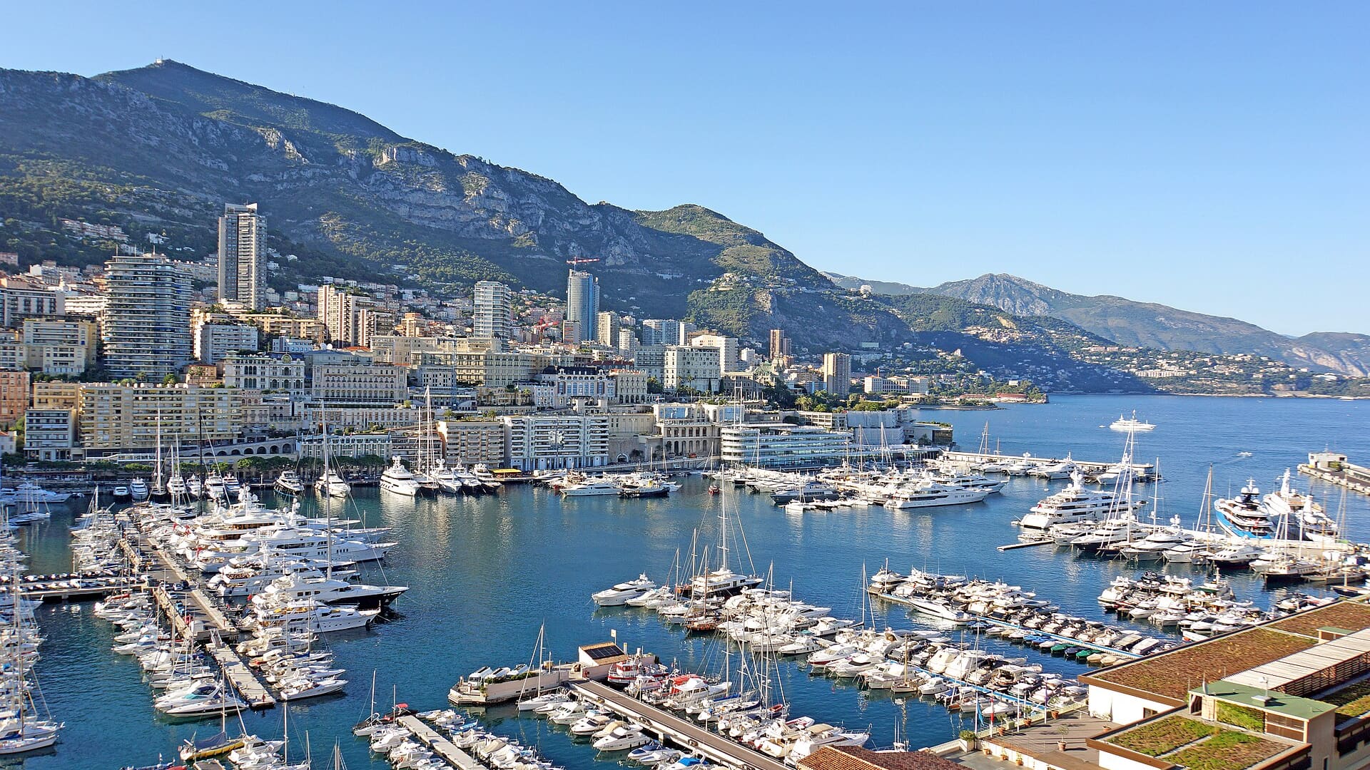 Aerial view of Monaco harbor with many yachts and city buildings