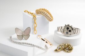 Assorted luxury jewelry and a watch displayed on white blocks