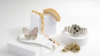 Assorted luxury jewelry and a watch displayed on white blocks