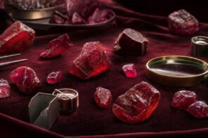 Rough Mozambique rubies with magnifying glass and gem tools on velvet