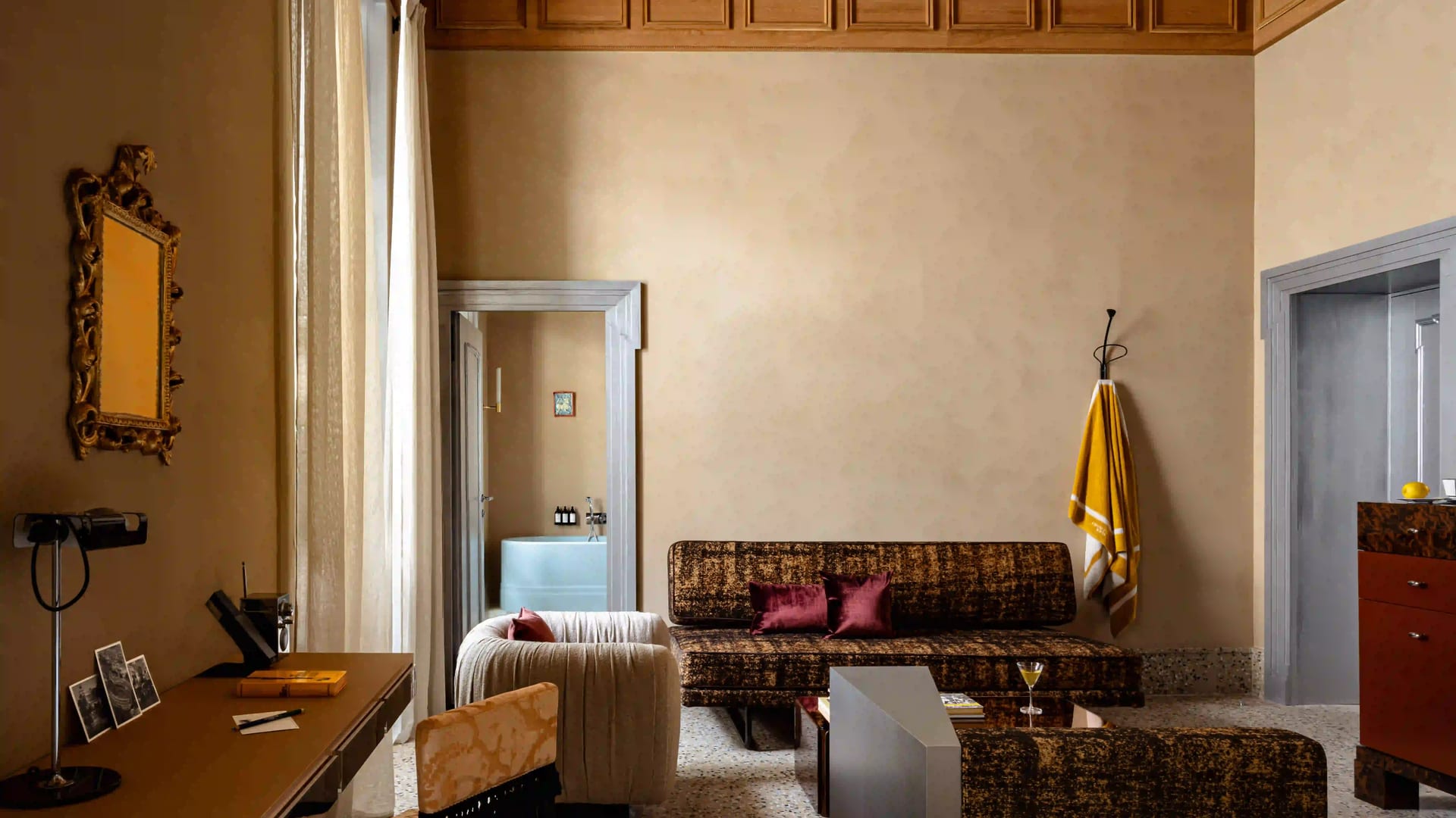 Experimental Roma suite with velvet sofas, desk, and bathroom with white tub