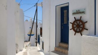 Whitewashed street with blue doors and ship wheel in Kato Chora, Serifos