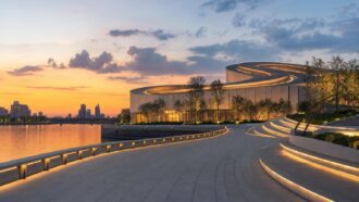 Shanghai Grand Opera House with spiraling rooftop beside the Huangpu River at sunset
