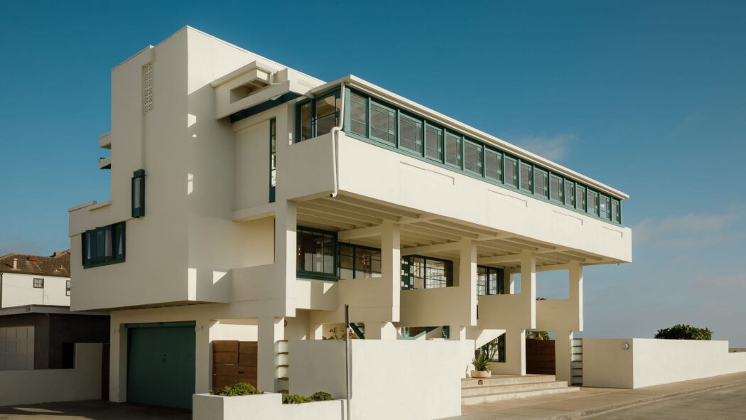Lovell Beach House with green-framed windows and elevated structure in Newport Beach