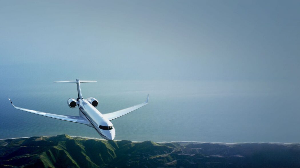 Private jet flying above coastline and mountains