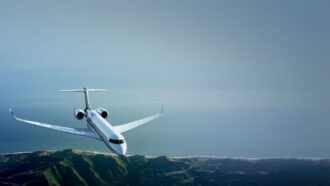 Private jet flying above coastline and mountains