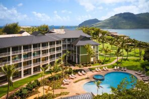 Hale Hōkūala Kauaʻi resort with pool, palm trees, and ocean in the background