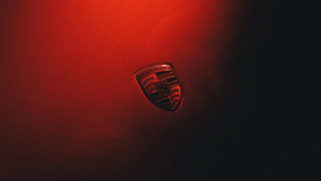 Porsche crest badge on a red-lit background