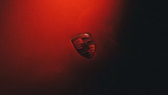 Porsche crest badge on a red-lit background